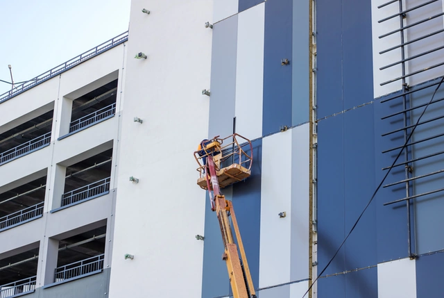 Painter using a lift to paint a commercial building exterior