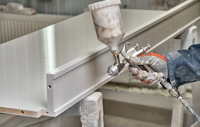 Spray gun applying paint to a cabinet door