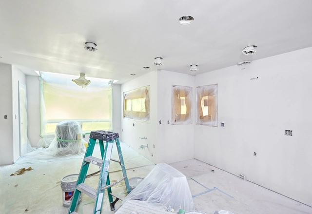 Interior room prepared for painting with protected floors and a ladder