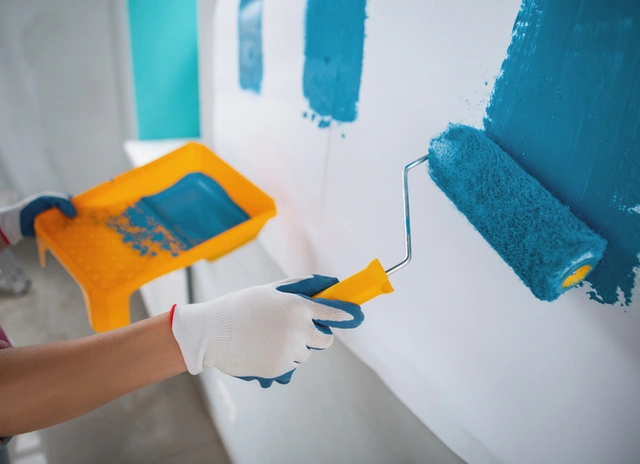Paint roller applying blue paint to a wall